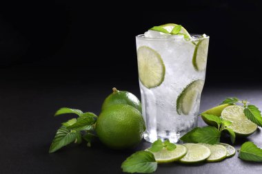 Siyah arka plan üzerine dilimlenmiş limon ile cam içki taze limon soda