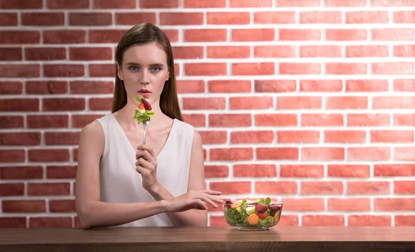 Beautiful young woman in joyful postures with hand holding salad