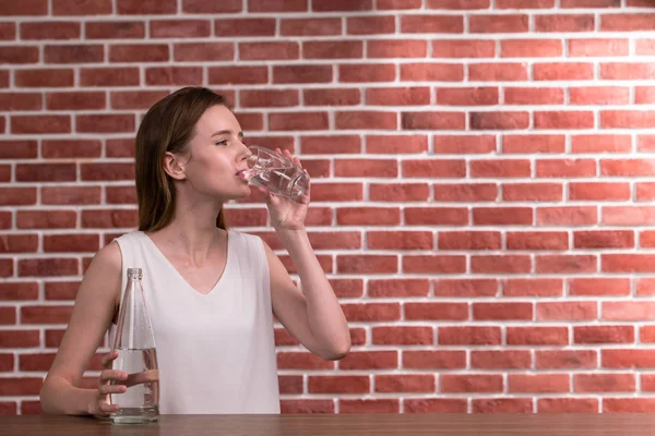 若い女性が部屋にガラスから水を飲む — ストック写真