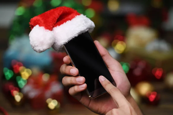 Hand Met Mobiele Telefoon Met Kerstman Hoed Boven Kerstmis Achtergrond — Stockfoto