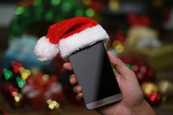 Hand Met Mobiele Telefoon Met Kerstman Hoed Boven Kerstmis Achtergrond — Stockfoto