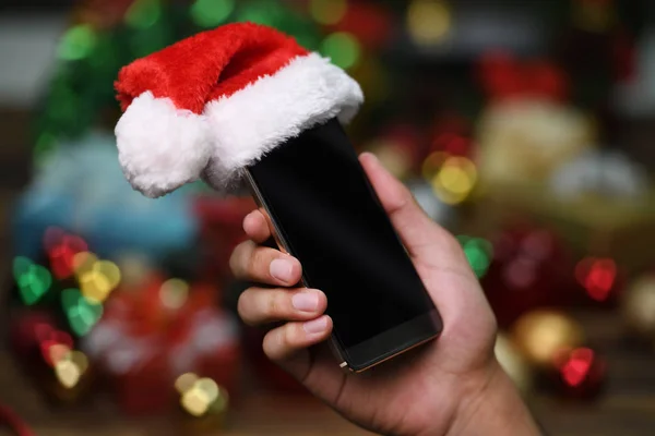 Hand Met Mobiele Telefoon Met Kerstman Hoed Boven Kerstmis Achtergrond — Stockfoto