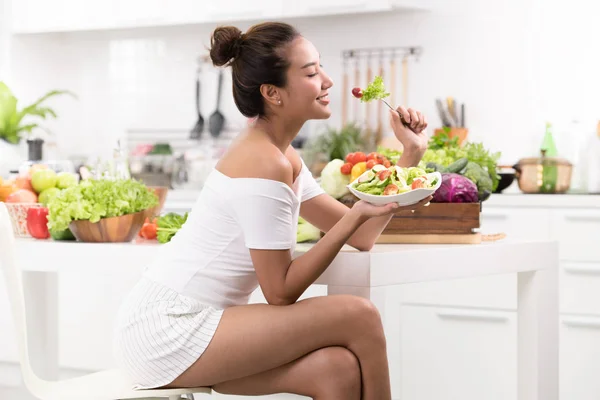 アジアの女性がキッチンでサラダを食べて — ストック写真