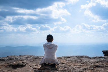 Doğal doğal görünüm ve güzel mavi gökyüzü bakan kayalık Dağı'nda oturan bir kişi
