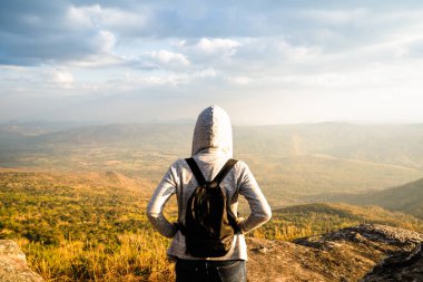 Doğal doğal görünüm ve güzel mavi gökyüzü bakan kayalık dağ üzerinde duran bir kadın