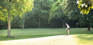 Asyalı kadın güzel doğal golf sahasında golf oynamak