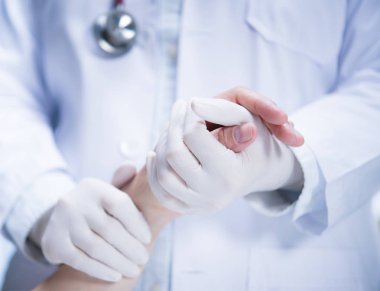 Tıp doktoru hastanın hastane ortamında destek vermek için elini tutarak lateks eldivenler