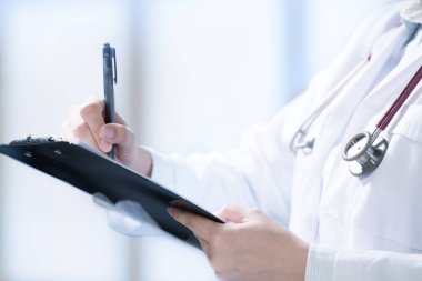 Hastane ortamında panoya not lar yazan ve not alan tıp doktoru