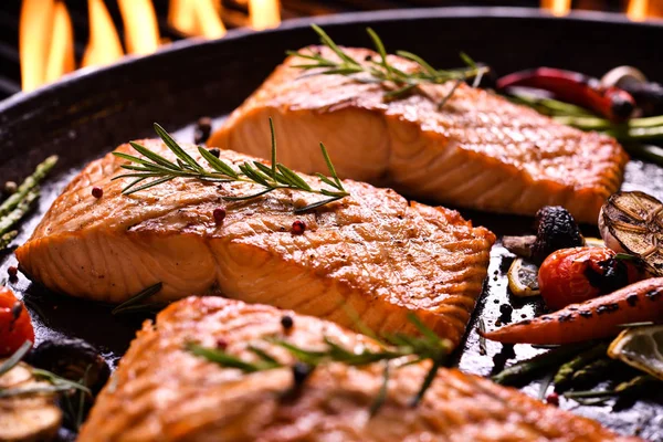 烤鲑鱼鱼与各种蔬菜在燃烧的烤架上的锅 — 图库照片