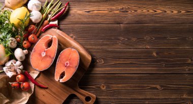 Ahşap arka planda otlar ve sebzeler ile taze çiğ somon balığı biftek