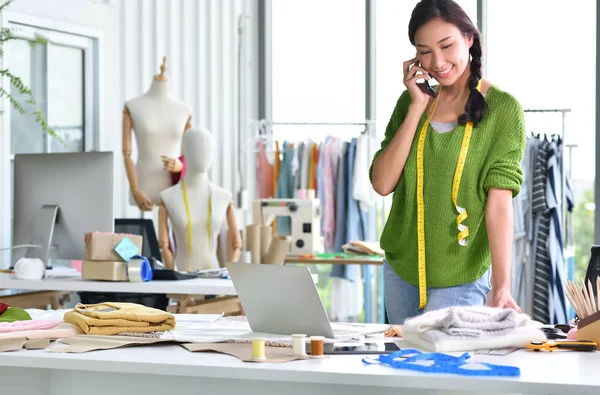 Young Asian woman entrepreneur / fashion designer working in studio