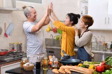 Mutfakta yemek pişiren anne ve babanın mutlu bir ailesi var. Birlikte sağlıklı yemekler yapıyorlar.