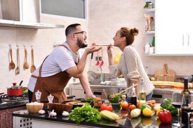 Genç Asyalı çifti sevmek mutfakta yemek yapmak birlikte sağlıklı yemekler yapmak eğlenceli.