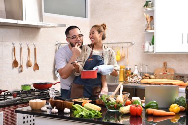 Genç Asyalı çifti sevmek mutfakta yemek yapmak birlikte sağlıklı yemekler yapmak eğlenceli.