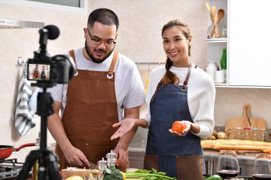 Genç Asyalı çift blogger vlogger ve çevrimiçi etkileyicisi mutfakta sağlıklı yiyecekler üzerine video içeriği kaydediyor