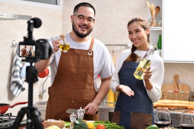 Genç Asyalı çift blogger vlogger ve çevrimiçi etkileyicisi mutfakta sağlıklı yiyecekler üzerine video içeriği kaydediyor