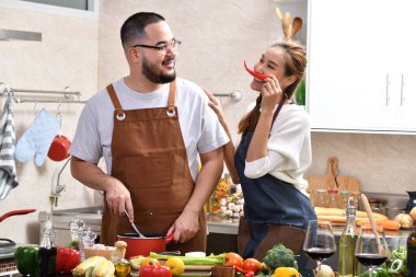 Genç Asyalı çifti sevmek mutfakta yemek yapmak birlikte sağlıklı yemekler yapmak eğlenceli.