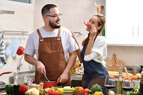 Genç Asyalı çifti sevmek mutfakta yemek yapmak birlikte sağlıklı yemekler yapmak eğlenceli.