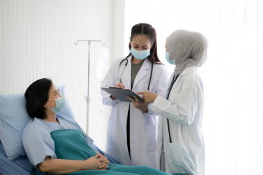 Korumalı vites takan ve hastane odasında hasta tedavi eden Asyalı kadın doktor.