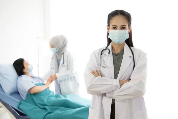 亚洲女医生在病房护理病人的背景下戴防护面罩的画像 — 图库照片