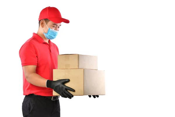 身穿红色制服 戴着医疗面罩 戴着防护手套的快乐的年轻亚洲送货员手拿着纸盒 与白色背景隔离 送货的人把包裹送来 安全分娩 — 图库照片