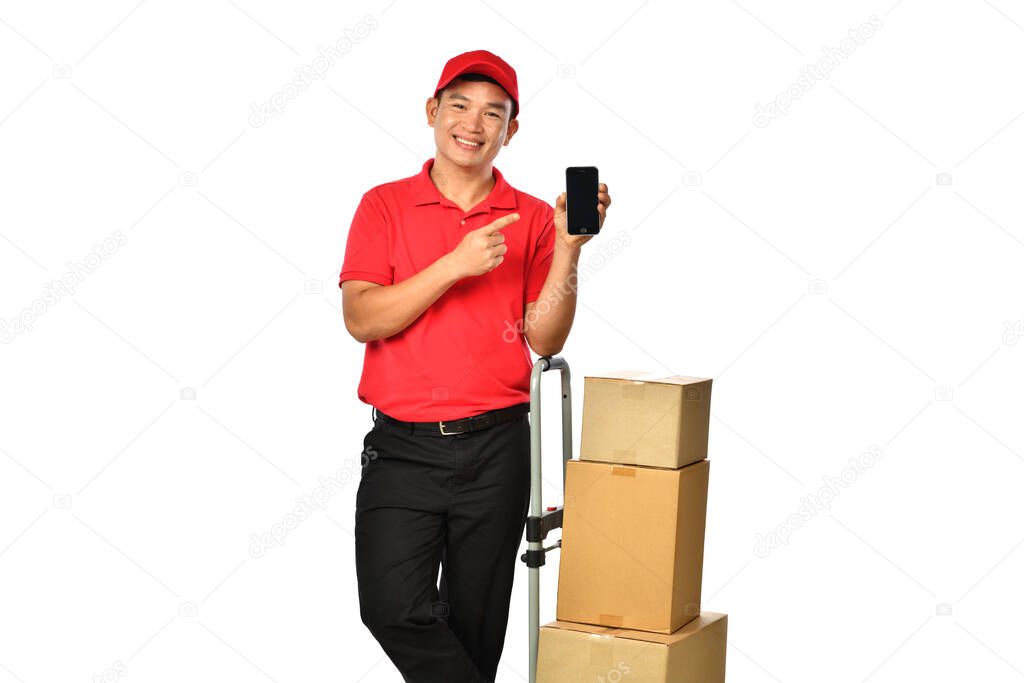 Asian delivery man in red uniform with parcel cardboard box showing mobile phone isolated on white background       