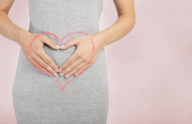 Genç bir kadının göbek eller tarafından düzenlenmektedir. boyalı bir kalple