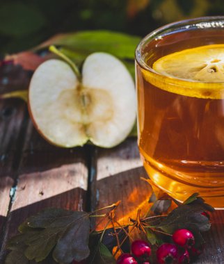 Şeffaf bir fincan çay ve limonla sonbahar kompozisyonu. Doğal bir arka planda. yakın plan.