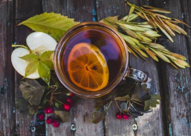 Şeffaf bir fincan çay ve limonla sonbahar kompozisyonu. Doğal bir arka planda. yakın plan.