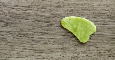 Yeşil Yeşim taşının doğal taşından yapılmış gua sha aracı. Boşluğu kopyala