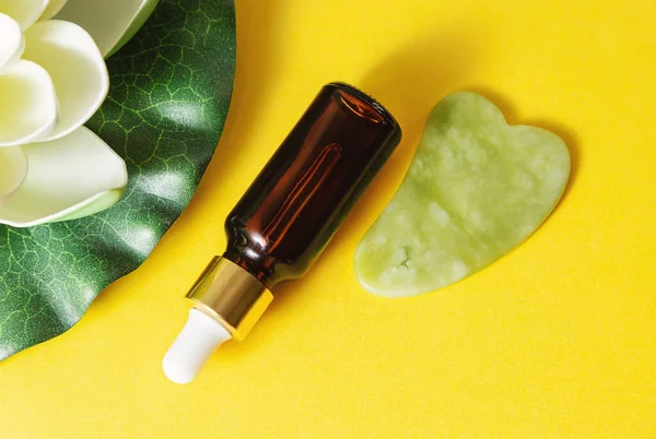 Sarı arka planda pipette ve yeşim taşlı cam şişe.