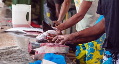 Tanınmayan kreollü adam, markette satılık ton balığı kesiyor..