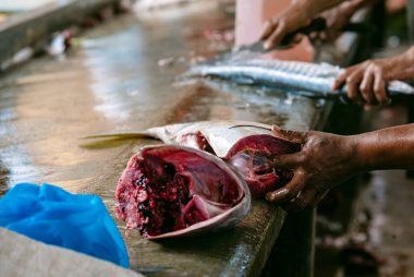 Tanınmayan kreollü adam, markette satılık ton balığı kesiyor..