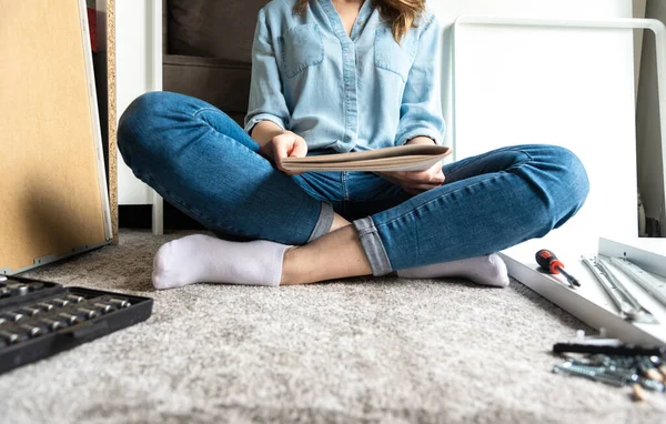 Woman reading instructions to assemble furniture at home