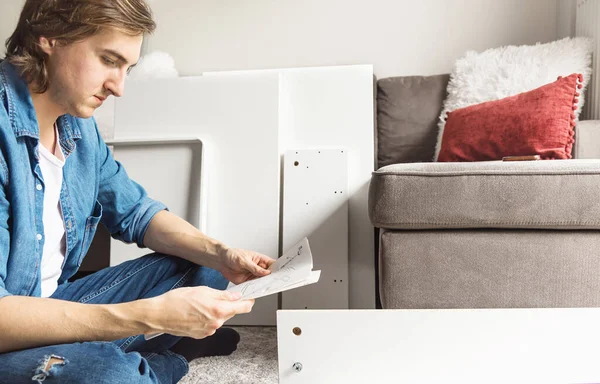 Joven Concentrado Leyendo Las Instrucciones Para Montar Muebles Casa Sala —  Fotos de Stock