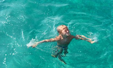 Denizde yüzen küçük bir çocuğun manzarası.