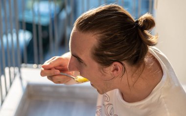 Tatlı kaşığı sarı karpuzla yiyen bir adam.