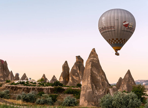 Big colorful hot air balloon flying against Nevsehir town in Cappadocia, Turkey 