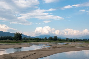 Yunanistan 'ın Kerkini Milli Parkı' nın arka planında küçük nehir ve bulutlu manzaralı çarpıcı bir manzara