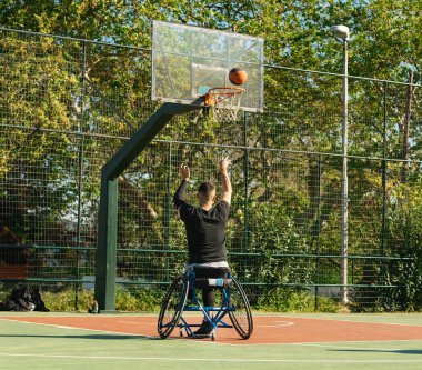 Tekerlekli sandalyedeki yakışıklı adam basketbol oynuyor.