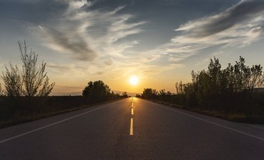 Arka planda dramatik gökyüzü ile otoyolda gün batımı