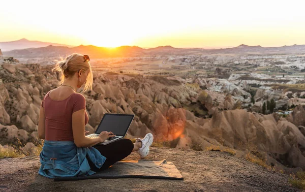 若いです女の子仕事ノートパソコンで日没で山の上で美しい景色と谷 — ストック写真