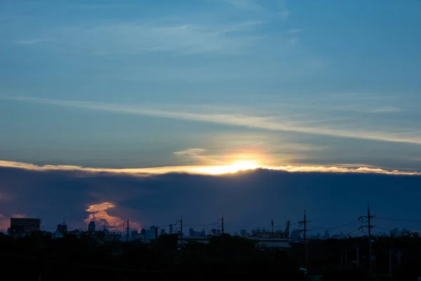 雲と夕日のイメージが市内の建物としての背景を持つイメージの中心の線を分割します — ストック写真