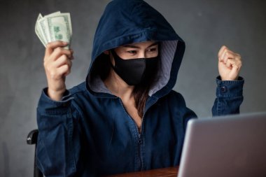 Profesyonel bilgisayar korsanı kadınlar, bilgisayar sistemlerinden veri çalarak dizüstü bilgisayar ve klavye konsepti olan kötü amaçlı yazılım ve hacker kullanarak sisteme virüs salan kapüşonlu mavi bir gömlek giyerler.