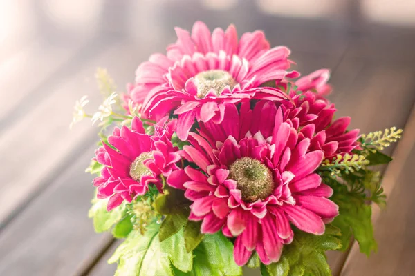 red, Burgundy flowers in a pot stand on a wooden table