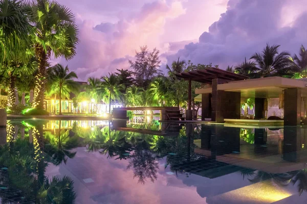 the purple reflection of the sky in the water in the evening. Palm trees, green plants and a beautiful sunset. hotel in Khao Lak, Thailand.