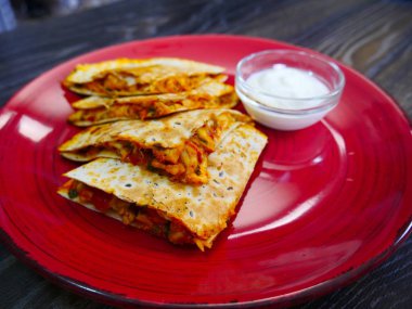 Quesadilla. Tavuk eti ve sebze. Krem souce üst. Tabakta güzel yemek.