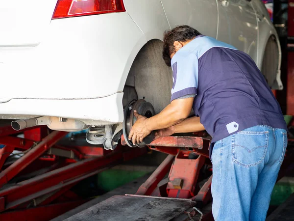 Tamircide araba çarkını değiştiren tamirci. 