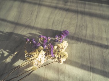 Güneş ışığı ile ahşap bir zemin üzerine yerleştirilen çiçekler