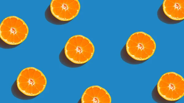 Colorful fruit pattern of fresh orange slices on blue background. From top view